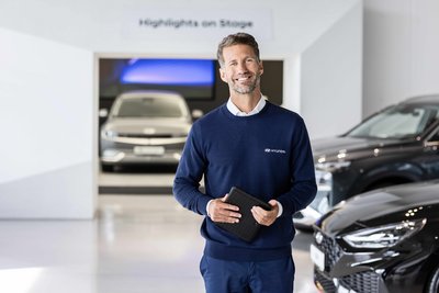 Mitarbeiter im Hyundai Autohaus Zondler steht im Showroom mit Tablet vor Fahrzeugen – Probefahrt Termin vereinbaren