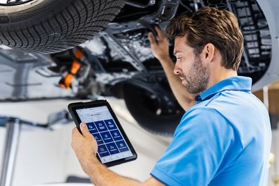 Kfz-Mechatroniker im Autohaus Zondler prüft ein Fahrzeug auf der Hebebühne und nutzt ein Tablet zur Diagnose und Planung von Serviceleistungen